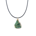 Detail of a natural green stone pendant with gold wire wrapping and black cord necklace - Aventurine Jade