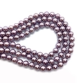 Macro shot of 4-10mm violet imitation glass pearls showing polished surface and drill holes - Purple
