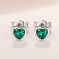 Macro detail of heart-cut green gemstone earrings with polished silver metal and butterfly backs - Green