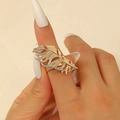 Détail d'une bague ouverte dorée en forme de plume avec texture ajourée portée au doigt - Or Plume Creuse (DZ-315)