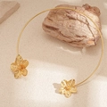 Detail of gold flower collar necklace showing intricate petal texture on stone background - Gold