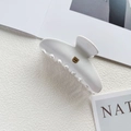 Detail of white acetate shark hair claw clip with gold B letter and magazine backdrop - Gold B Logo / White
