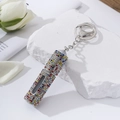 Detailed view of rhinestone lipstick keychain atomizer on elegant decorative stone - Colorful Zirconia