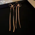 Vue macro de boucles d'oreilles nœud en or rose avec longues chaînes à pompons sur velours - Gland en Forme de Ruban de Nœud Papillon (25# Tige d'Oreille en Argent - Or)