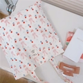 Dettaglio della borsa tote in cotone bianco con motivi di conigli e ciliegie sulla scrivania - Fiocco Coniglio