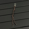 Detail of a brown woven paracord bag charm with reflective stitching and silver metal clasp - Coffee
