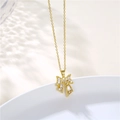 Dettaglio della collana a fiocco dorata con zirconi bianchi su un piatto di ceramica bianca - Oro
