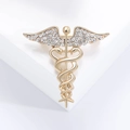 Broche Caduceo dorado con vara de serpiente alada y detalles de diamante sobre blanco - Dorado