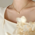 Elegante 18K vergulde titanium ketting met ovale parelhanger gedragen door een model - Parelketting / Goud