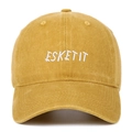 Close-up of ESKETIT white embroidery on a washed ginger cotton baseball cap detail - Yellow