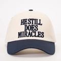 Adjustable two-tone baseball cap with HE STILL DOES MIRACLES embroidery on white background - Cream/Navy Blue