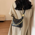 Chic black quilted bucket bag with gold chain strap on beige trench coat model - Black