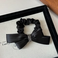 Eleganter schwarzer Satin-Haargummi mit Kristallbesatz auf einer weißen Dekorationskarte - Schwarzes Satin-Schleife Haargummi mit Strass