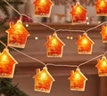 LED Christmas light string with glowing wooden house charms in warm yellow light - Painted Christmas House