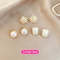 Vista dettagliata di 3 paia di orecchini a fiore e perla dorati su seta color champagne - Set da 3 Paia-Fiore Perla Tonda Geometrico / Oro-Bianco