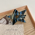 Makro-Detail der Y2K Stern-Haarklammer aus Acetat mit Marmormuster und TA-Anhänger - Blau-Schwarz Gestreift