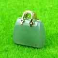 Mini green crystal gemstone handbag pendant with golden handle on grass background - Green Aventurine