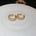 Close-up of golden irregular multi-layer hoop earrings on a white striped plate - Gold C-Shape Silver Earring Post (Multi-layer)