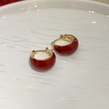 Detail view of red enamel gold earrings displayed on a white textured plate - 91# Earring - Red
