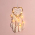Atrapasueños blanco en forma de corazón con luces LED y plumas sobre fondo rosa - Lino con Luces