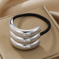 Detail of silver metallic ponytail holder with triple curved bars on silk background - Silver Triple Layer Smooth