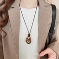Macro view of teardrop amber-textured acrylic pendant on long black wax cord necklace - 63# Necklace-Light Brown