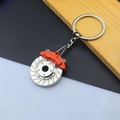 Macro shot of silver metal brake disc keychain with vibrant orange caliper detail - Brake Disc / Orange