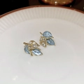 Close-up of vintage leaf earrings with blue enamel, gold edges, and crystal accents - Silver Pin - Blue Rhinestone Leaf Stud Earrings