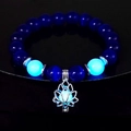Luminous lotus flower pendant charm bracelet with glowing blue beads in a dark setting - 10mm Royal Blue Cat's Eye with Blue Light
