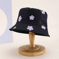 Close-up of black cotton bucket hat with purple flowers and smiley faces on a wooden stand - Kids One Size / Black (Smile Flower Print)