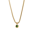 Macro detail of gold snake chain necklace with a green gemstone set in a sphere pendant - Green