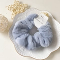 Soft faux fur scrunchie in smoky blue color on a decorative white porcelain plate - Light Blue