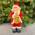 Electric Santa Claus figurine with golden saxophone and festive red suit by Christmas tree - Santa Playing Saxophone