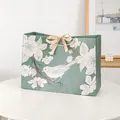Elegant sage green gift bag with floral patterns and a golden satin bow on a white table - Small (18x16x10cm) / Gold Ribbon