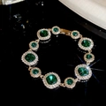 Makro-Detail eines Luxus-Smaragdarmbands mit runden Diamanten-Fassungen auf Schwarz - Armband - Gold - Grün