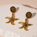 Detailed view of vintage gold starfish earrings on a white plaster stone pedestal - S925 Silver Pin / Gold