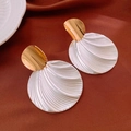 Detailed view of round textured earrings with gold and silver dual-tone finish on red silk - Gold