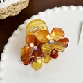 Amber acetate flower hair claw clip with rhinestones shown on a white ceramic plate - 6.1cm / Brown