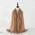 Close-up of camel cotton linen scarf with soft pleated texture and fringe edges - Camel