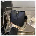 Detail der schwarzen Leder-Beuteltasche mit goldener Schließe und gemustertem Schultergurt - Schwarz