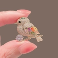 Golden bird brooch with colorful gemstones and hanging crystal, held for scale - 236# Little Bird