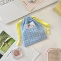Blue plaid drawstring pouch with yellow rope and colorful label on a desktop setup - Blue Plaid
