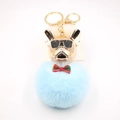 Dettaglio portachiavi con pompon blu, ciondolo bulldog dorato e occhiali da sole - Azzurro