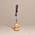 Detail eines handgeschnitzten Hasen-Schlüsselanhängers aus Holz mit Fu-Perle und Kordel - Schlüsselanhänger Hase