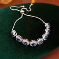 Detailed macro view of an adjustable silver bracelet with seven oval blue zircons - Blue