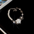 Detalle de pulsera de perlas con dije de flor blanca y pedrería brillante en cadena de plata - Pulsera-Plata-Flor Blanca