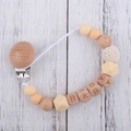 Detail of wooden baby pacifier clip with silicone beads and 'BABY' letter cubes - Nude