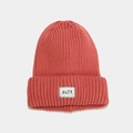 Detail of coral knit beanie showing thick ribbed texture and a white brand label patch - Dusty Pink