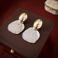 Dettaglio di orecchini a ventaglio oro e argento su una scatola di gioielli in pelle - Oro e Argento
