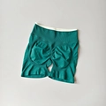 Close-up of seamless dark green yoga shorts featuring scrunch butt and white waistband - Dark Green